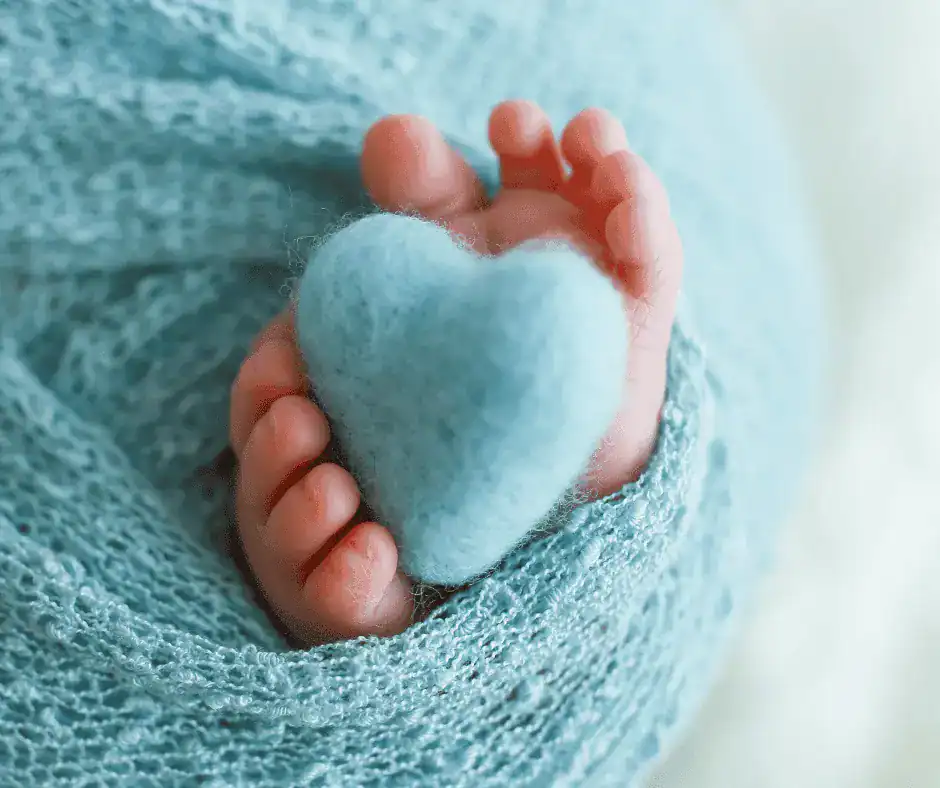 a babys feet wrapped in a blue blanket with a blue heart
